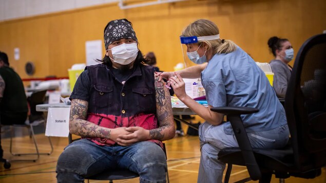 Tinuturukan ng health-care worker ang isang lalaki na naka-mask sa loob ng basketball court.