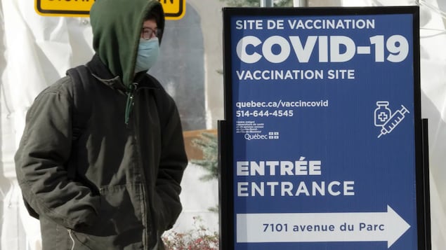 Isang lalaki na naka-jacket, salamin at mask papasok ng COVID-19 vaccination site.加拿大免疫委員會建議50歲以上加拿大人打新冠疫苗加強針。