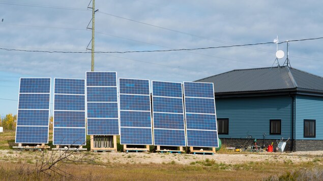 Des panneaux solaires derrière un édifice bleu