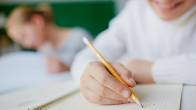 Image d'un élève en classe utilisant un crayon de bois.