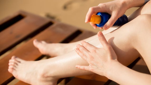 Quelqu'un s'applique de la crème solaire sur les jambes.