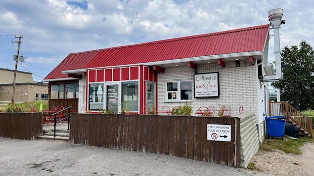 Extérieur d'un bâtiment commercial à toit rouge portant l'enseigne "La Crêperie de la Reine".