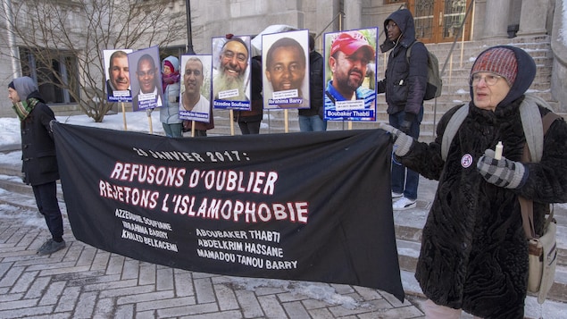 Des gens tiennent une banderole et des affiches.