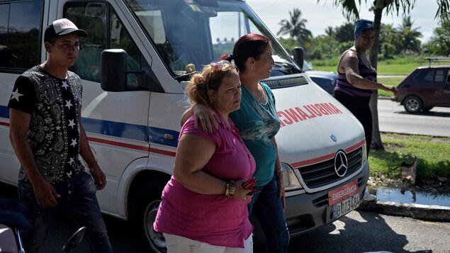 Des Cubains marchent à côté d'une ambulance. Des Cubains marchent à côté d'une ambulance.