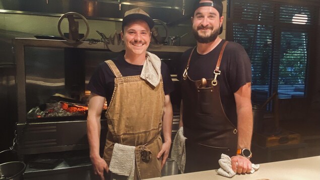 Deux cuisiniers se tiennent dans la cuisine d'un restaurant.