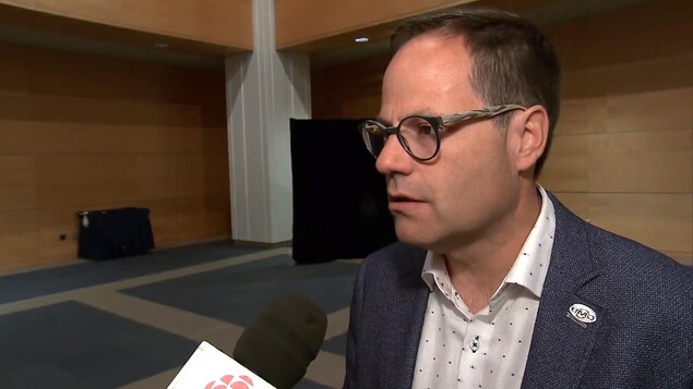 Plan rapproché d'Alexandre Cusson, devant un micro.