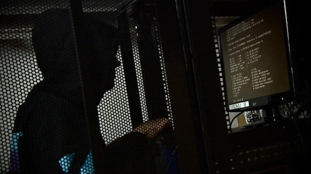 Une reconstitution d'un cybercriminel devant un écran d'ordinateur