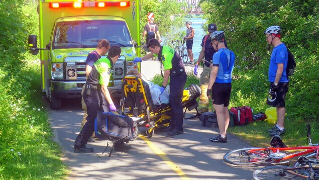 Des ambulanciers paramédicaux interviennent sur une piste cyclable.