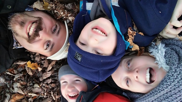 Deux adultes et deux enfants sourient dans un tas de feuilles mortes l'automne. Deux adultes et deux enfants sourient dans un tas de feuilles mortes l'automne.