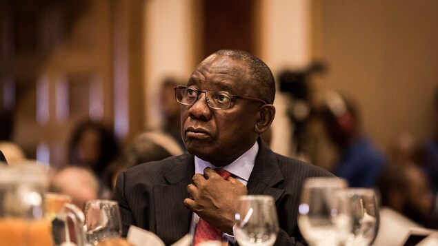 Cyril Ramaphosa, assis à une table, arrange sa cravate. Cyril Ramaphosa, assis à une table, arrange sa cravate.