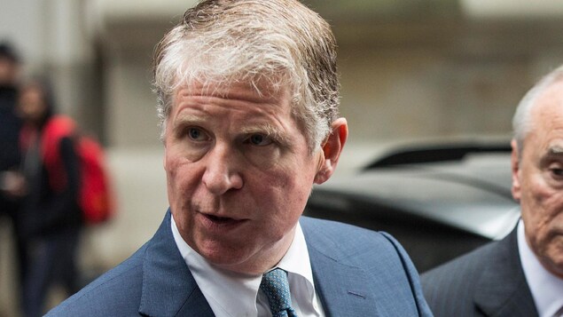 Le procureur de Manhattan, Cyrus Vance, regarde sur le côté, un homme derrière lui en fait de même. Le procureur de Manhattan, Cyrus Vance, regarde sur le côté, un homme derrière lui en fait de même.