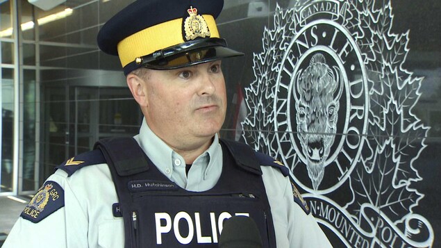 Le policier Dal Hutchinson en uniforme devant un logo de la GRC. Le policier Dal Hutchinson en uniforme devant un logo de la GRC.
