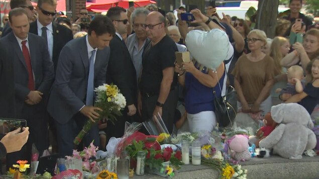 Un homme en complet se penche, un bouquet de fleurs à la main. Un homme en complet se penche, un bouquet de fleurs à la main.