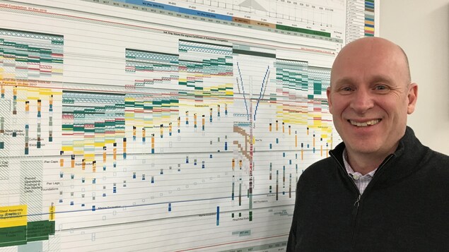 Daniel Genest, directeur de la coordination du projet du nouveau pont Champlain, devant un tableau de l'échéancier