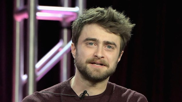 Daniel Radcliffe porte un chandail bordeaux. 
