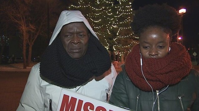Le père et la sœur de Promise « Max » Chukwudum de face portant une pancarte affichant « Missing », disparu en anglais.