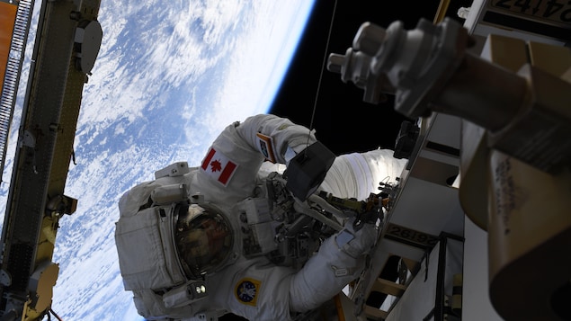 David Saint-Jacques procède à des travaux sur la Station spatiale internationale, avec la Terre en arrière-plan. 