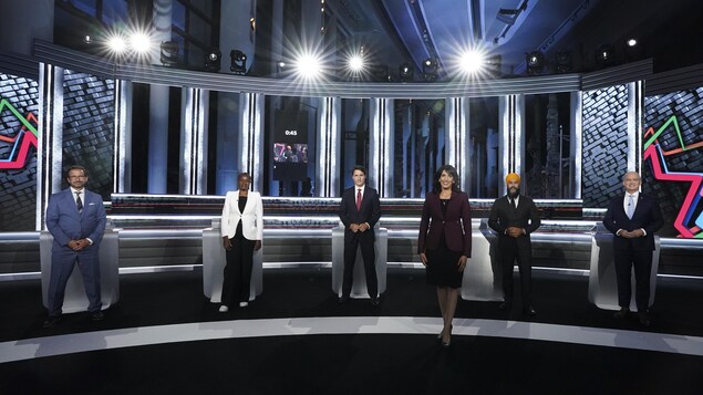 Shachi Kurl pose à l'avant-plan sur le plateau du débat, avec les chefs à l'arrière.