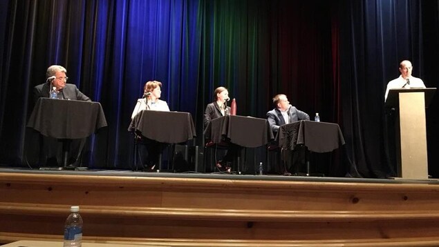 Une photo du débat. Quatre candidats sont près l'un de l'autre dans un auditorium. Une photo du débat. Quatre candidats sont près l'un de l'autre dans un auditorium.