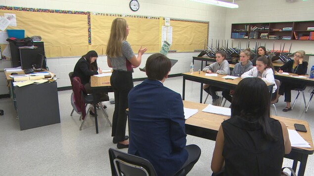 Des élèves sont assis en classe et écoutent une personne en train de parler.