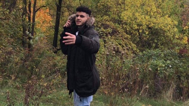 Yassin Dabeh porte un manteau d'hiver et pose devant une forêt.