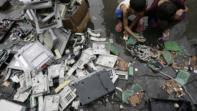 À Manille, des enfants recherchent des morceaux de cuivre parmi une pile de déchets électroniques. À Manille, des enfants recherchent des morceaux de cuivre parmi une pile de déchets électroniques.