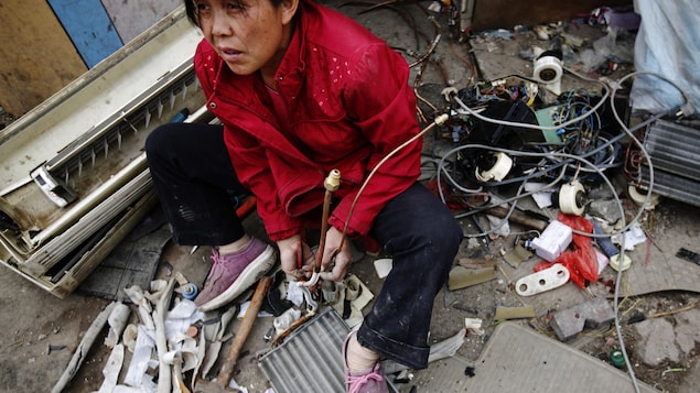 À Pékin, une femme sépare les pièces d'un air climatisé et est entouré de fils et de morceaux de plastique. À Pékin, une femme sépare les pièces d'un air climatisé et est entouré de fils et de morceaux de plastique.