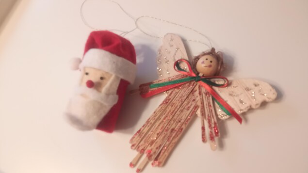 Deux décorations de Noël, une présentant un Père Noël et l'autre un bois, déposés sur une table. 