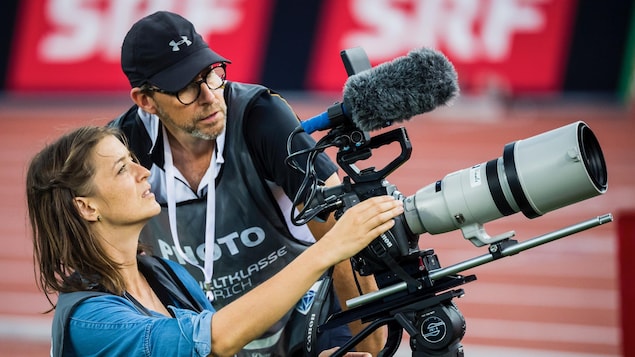 Camérawoman et réalisateur qui regardent dans la lentille de la caméra sur une piste de course.
