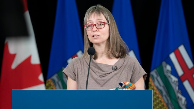Deena Hinshaw, lors d'une conférence de presse, devant des drapeaux du Canada et de l'Alberta.