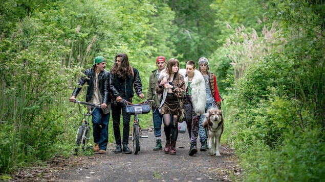 Un groupe de jeunes marchent sur un chemin avec un chien.