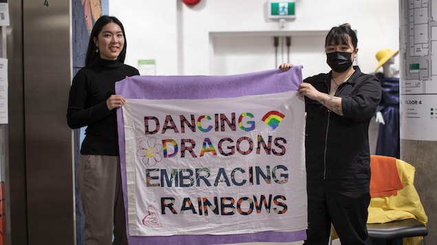 兩個人手持一張寫著"舞龍擁抱彩虹"的橫額。