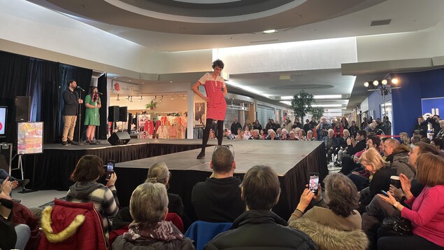 Une femme sur une scène dans un centre commercial lors d'un défilé de mode.