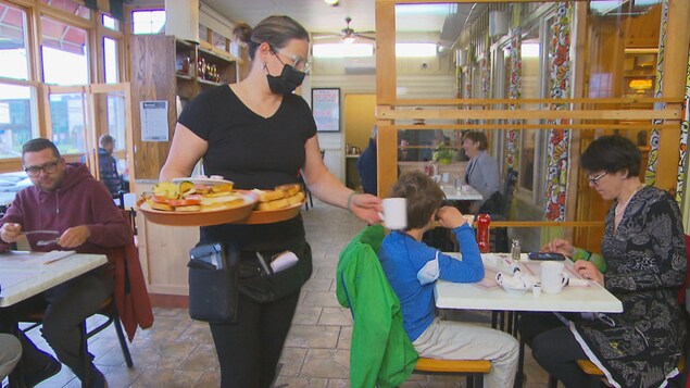 Une serveuse porte des assiettes.