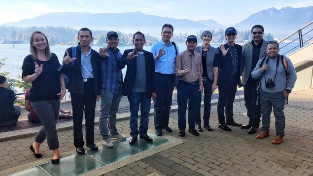 Un groupe de dix personnes pose avec des montagnes en arrière-plan. Un groupe de dix personnes pose avec des montagnes en arrière-plan.