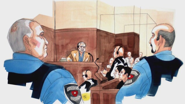 Un homme comparaît dans une salle d'audience devant des avocats, des policiers et un jury.