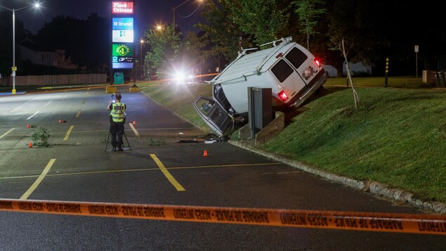 Une camionnette accidentée et un policier qui colligent des indices.