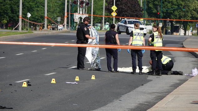 Des policiers auprès d'une victime au sol sur la scène d'un délit de fuite mortel.