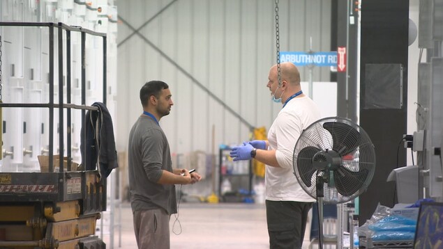 Deux hommes parlent dans une usine. Deux hommes parlent dans une usine.