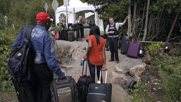 Un policier parle avec des migrants.