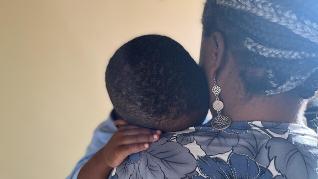 Une femme tient dans ses bras son enfant, dont la tête est posée sur son épaule.