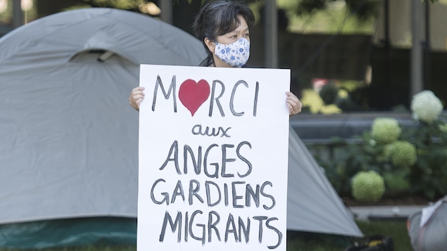Une manifestante avec un panneau remerciant les anges gardiens.