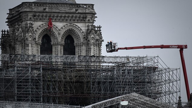 Une nacelle est au-dessus d'un gigantesque échafaudage, près des beffrois de la cathédrale.