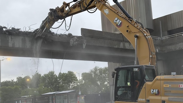 Une pelleteuse détruit une passerelle.
