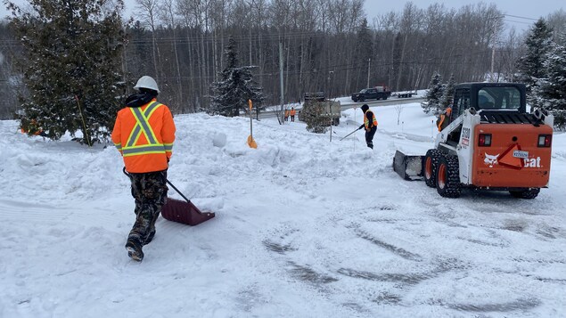 Des travailleurs déneigent un terrain. 