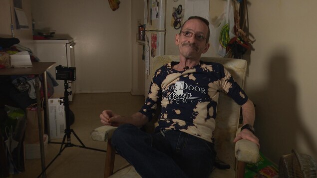 Denis Pilon, assis dans un fauteuil devant la caméra. Denis Pilon, assis dans un fauteuil devant la caméra.