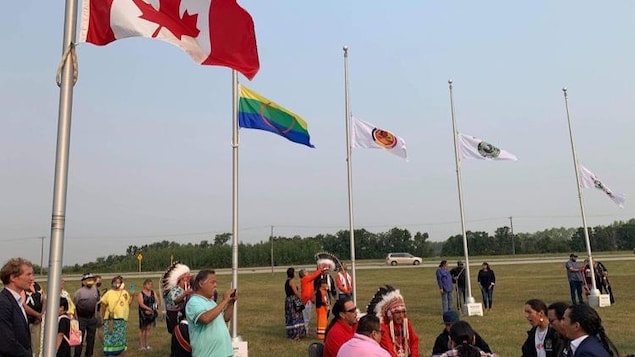 Un groupe de personnes jouent du tambour et les drapeaux sont levés.