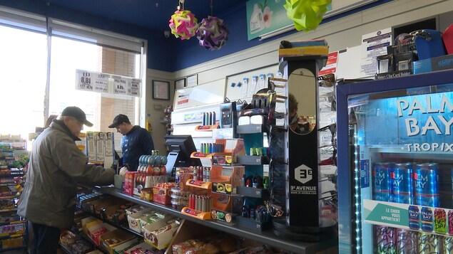 Un client paye au comptoir d'un dépanneur