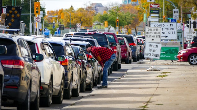 Des gens dans leur voiture sont dans une longue file pour se faire dépister.
