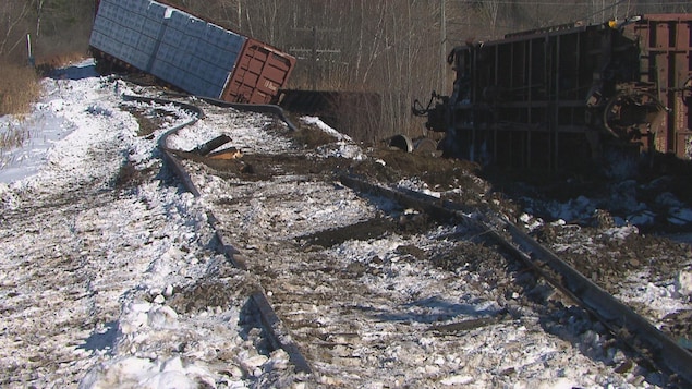 Deux wagons sont détachés l'un de l'autre et sont renversés sur le côté. Les rails sont arrachés et ont dévié de leur trajectoire.